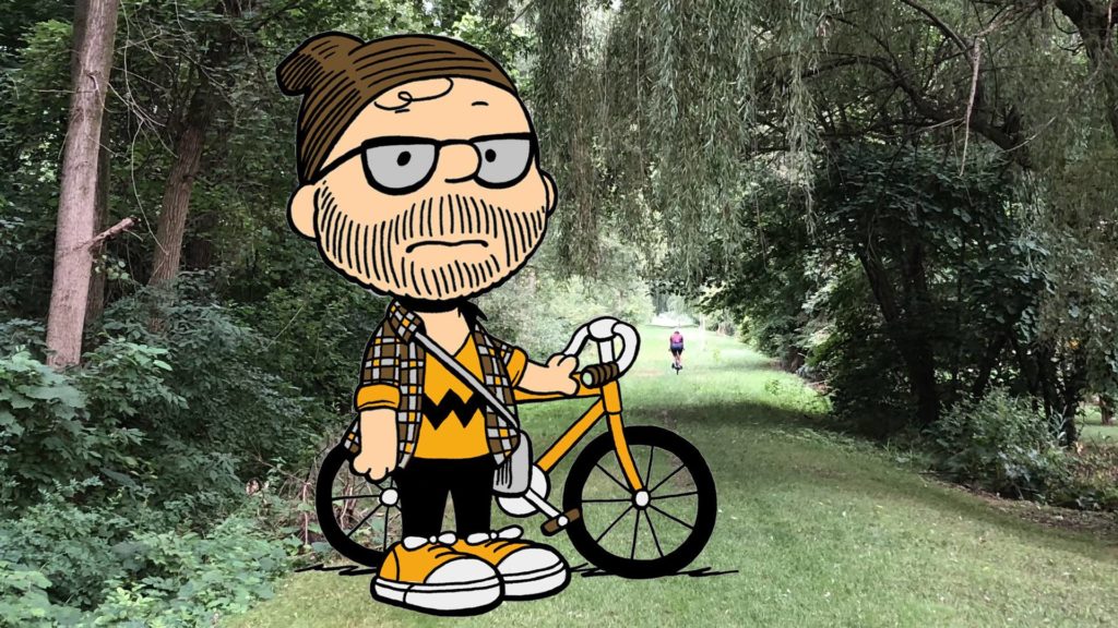 Illustrated Peanut Roll mascot with bike on the grassy Peanut Line trail.