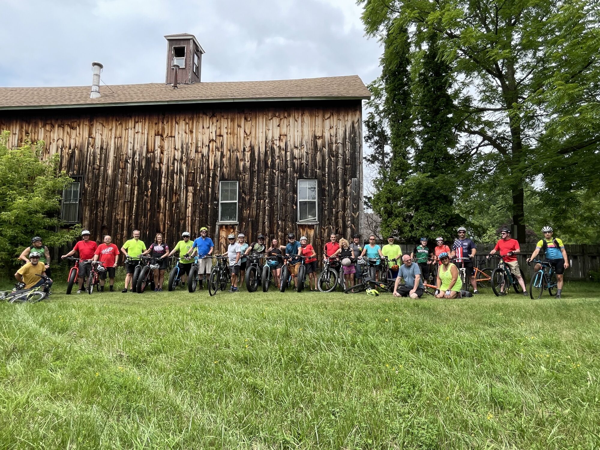 Group of bicyclists in front of the barn.